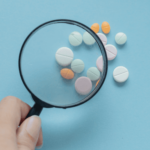 A magnifying glass examining pills for FDA approval