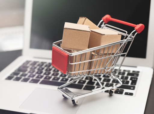 A small shopping cart sitting atop laptop keyboard, symbolizing e-commerce